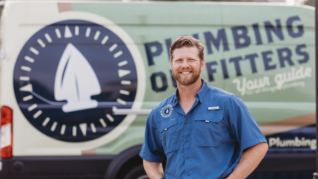 Plumbing Outfitters technician in front of a Central Texas home at golden hour